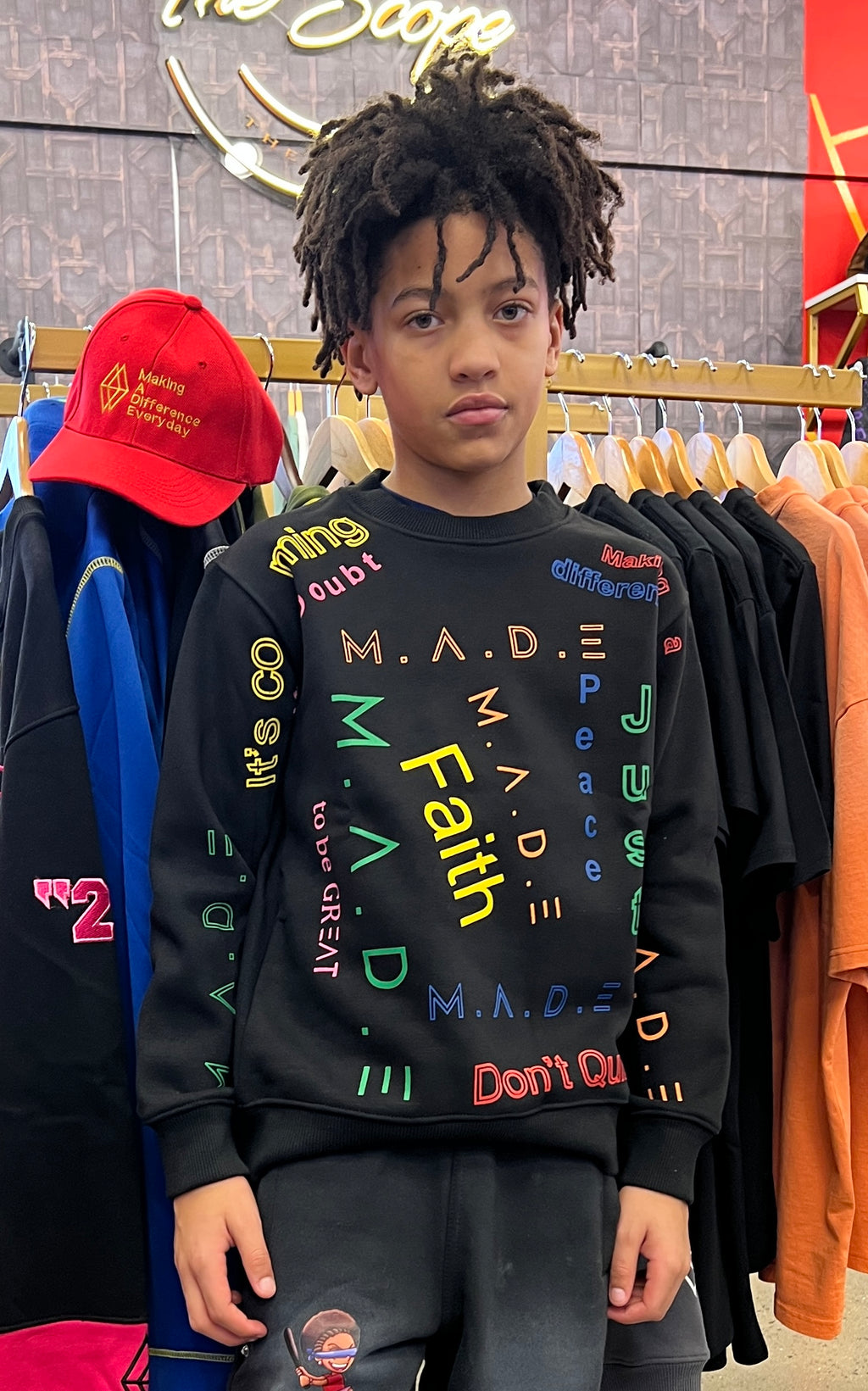 Young person wearing a black sweatshirt with colorful text in a clothing store